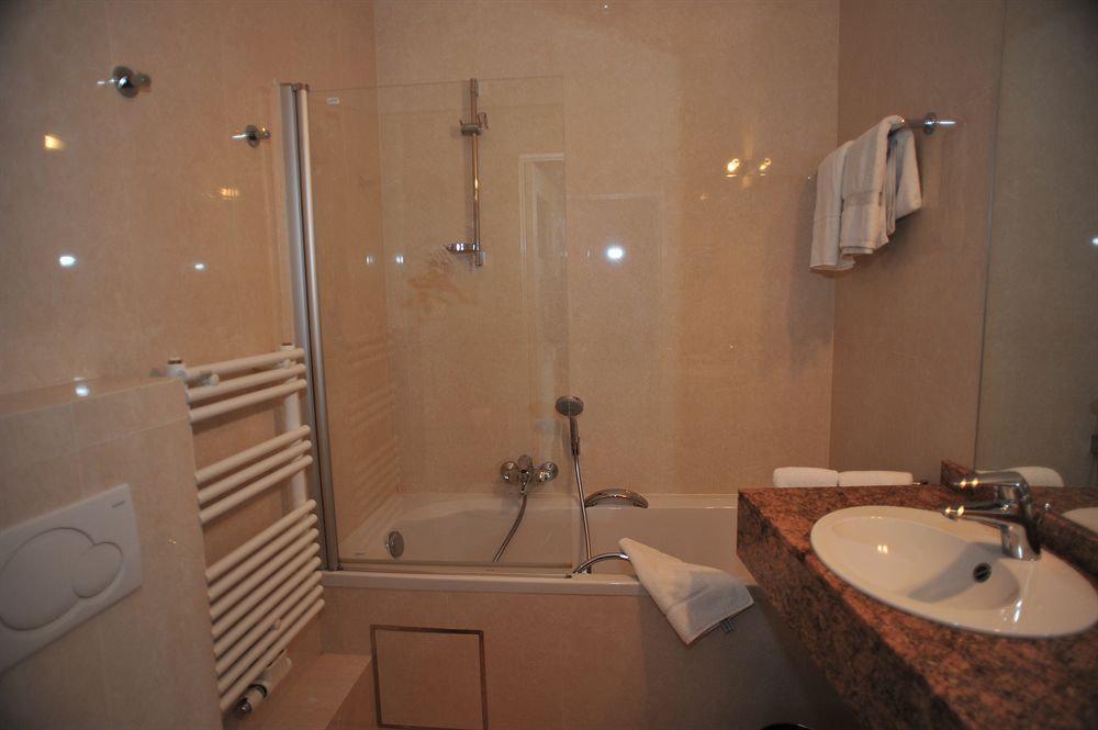 Badkamer met bad, douchewand en wastafel